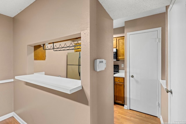 hallway featuring light wood-type flooring and a textured ceiling