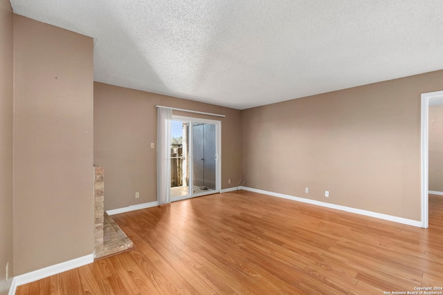 spare room with light wood-type flooring and a textured ceiling