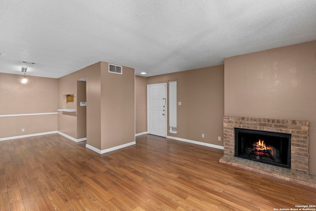 unfurnished living room featuring hardwood / wood-style flooring, a fireplace, and a textured ceiling