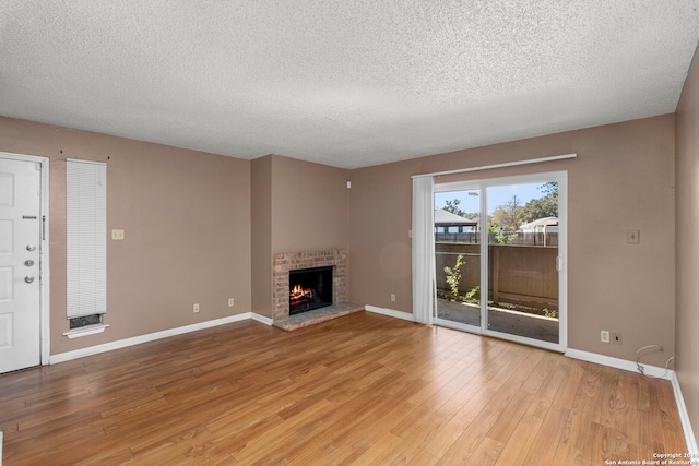 unfurnished living room featuring a textured ceiling, light hardwood / wood-style floors, and a fireplace