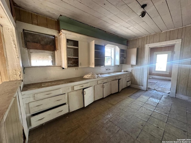 kitchen featuring cream cabinets, wooden walls, and wood ceiling