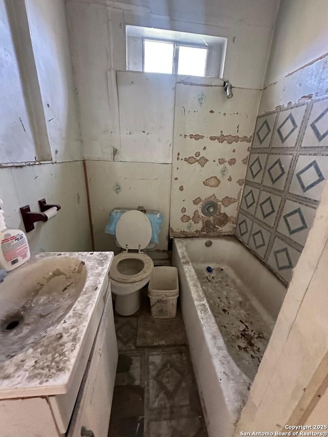 bathroom featuring vanity, a bath, and toilet