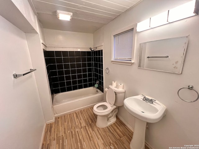 full bathroom featuring hardwood / wood-style flooring, toilet, tiled shower / bath, and sink