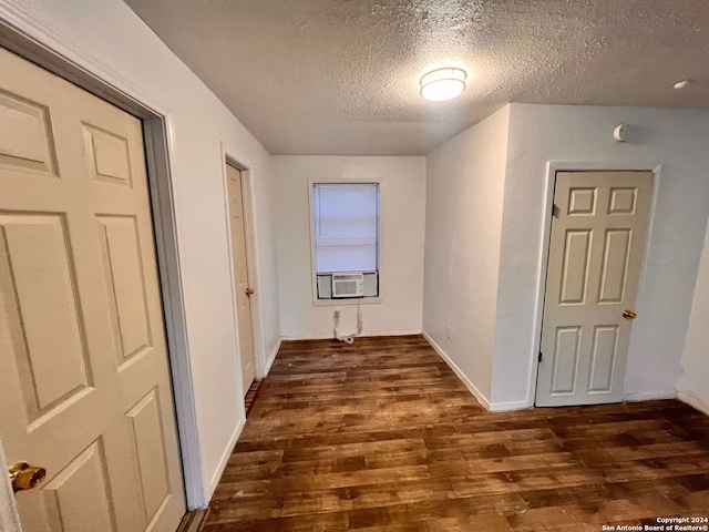 corridor featuring dark hardwood / wood-style flooring, cooling unit, and a textured ceiling