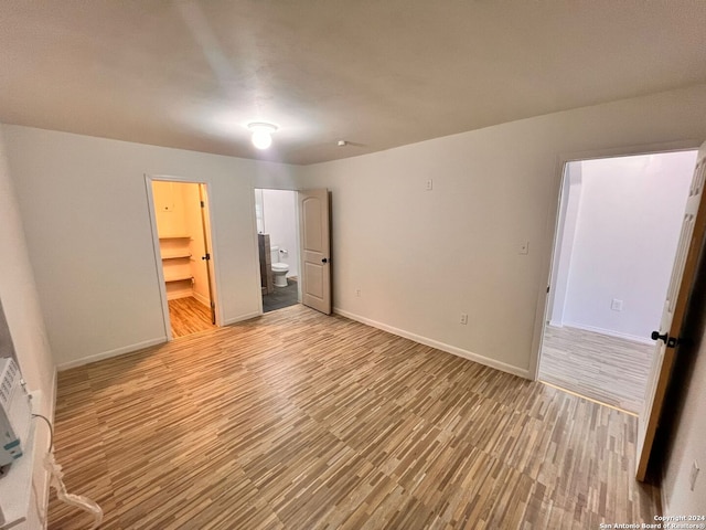 unfurnished bedroom with a spacious closet, a closet, and light hardwood / wood-style floors