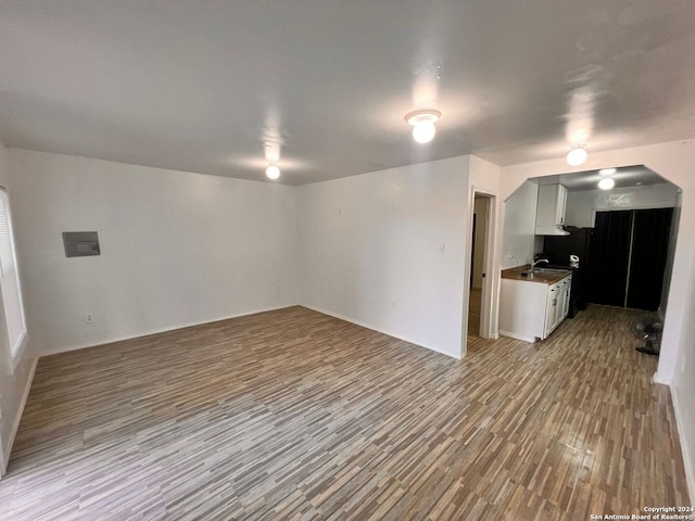 unfurnished living room featuring sink and light hardwood / wood-style floors