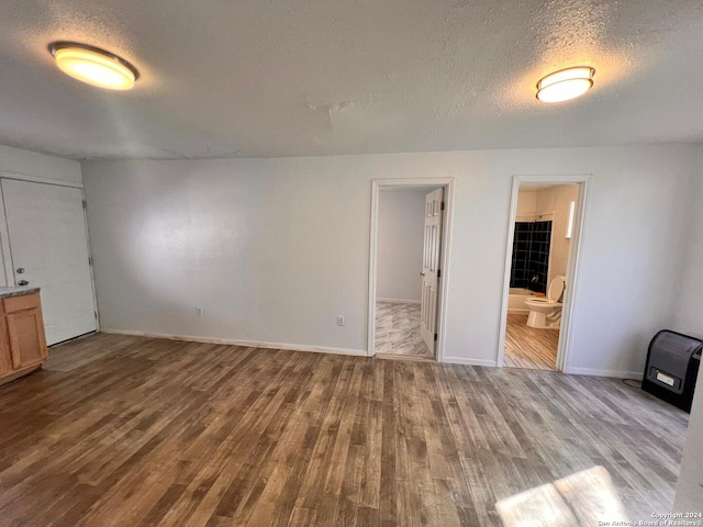 unfurnished bedroom with a walk in closet, a textured ceiling, connected bathroom, light hardwood / wood-style floors, and a closet