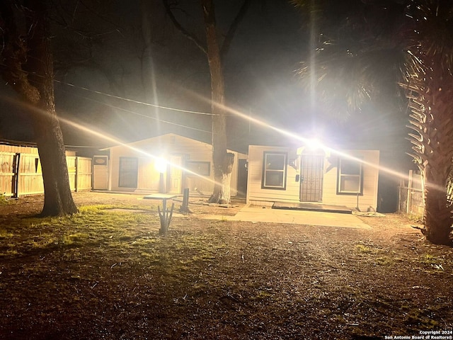 back house at night featuring a patio area