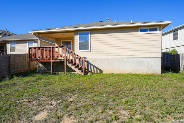 rear view of house featuring a wooden deck and a lawn