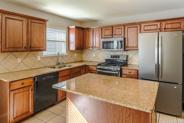 kitchen with appliances with stainless steel finishes, a center island, light stone counters, and sink