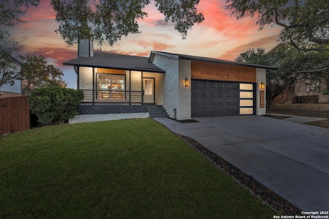 modern home featuring a porch, a garage, and a yard