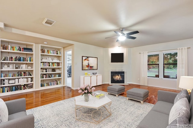 living room featuring built in shelves, ceiling fan, and hardwood / wood-style flooring