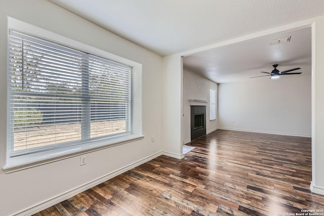 unfurnished living room with dark hardwood / wood-style flooring, ceiling fan, and plenty of natural light