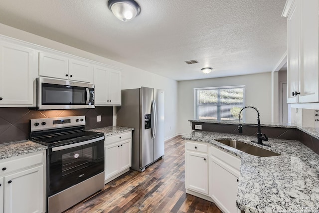 kitchen with light stone countertops, stainless steel appliances, white cabinetry, and sink