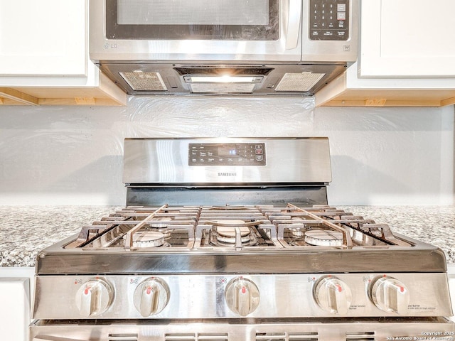 kitchen with white cabinets, light stone counters, and range