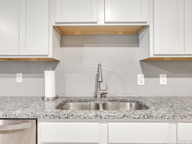 kitchen with white cabinets, dishwasher, light stone countertops, and sink