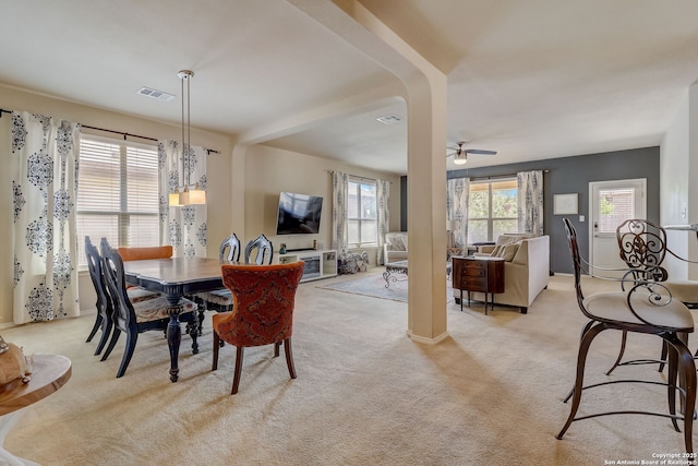 carpeted dining area featuring ceiling fan with notable chandelier