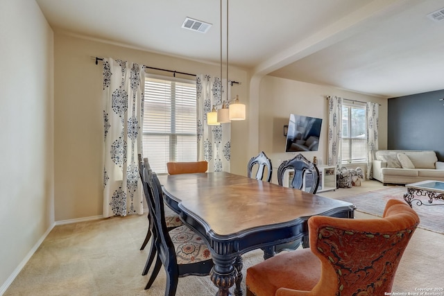 carpeted dining space featuring beam ceiling