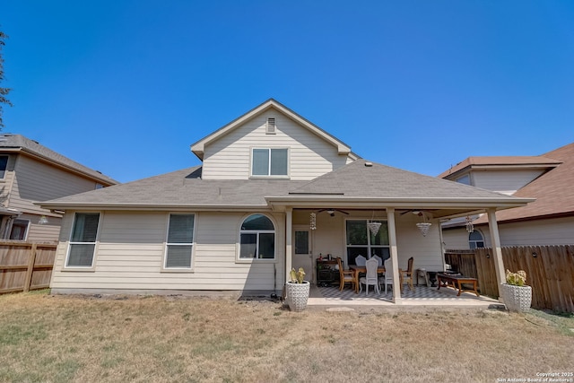 back of property with a lawn, a patio area, and ceiling fan