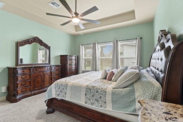 carpeted bedroom featuring ceiling fan and a raised ceiling