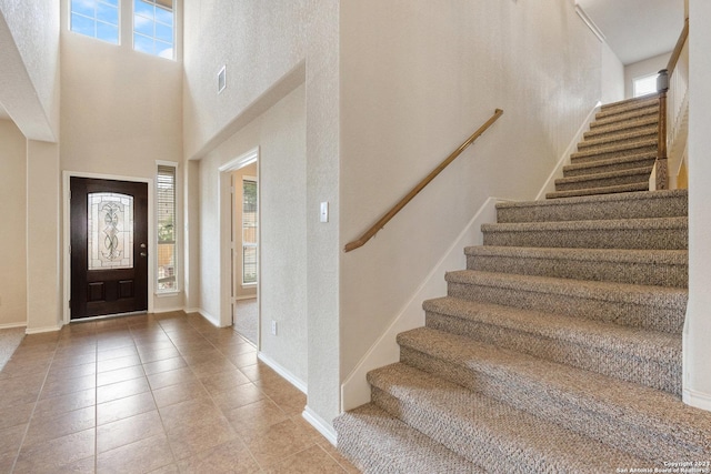 entryway with light tile patterned floors and a towering ceiling