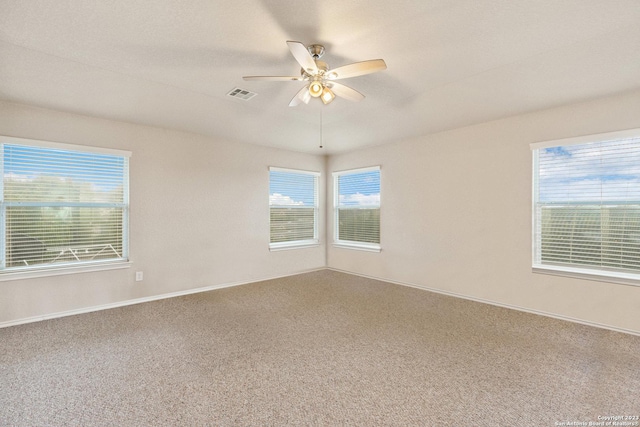 carpeted empty room with a wealth of natural light and ceiling fan