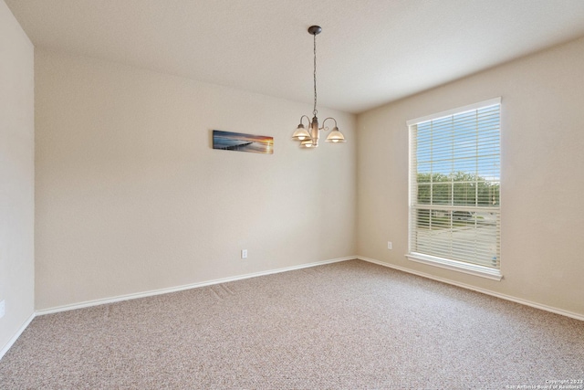 carpeted empty room with an inviting chandelier