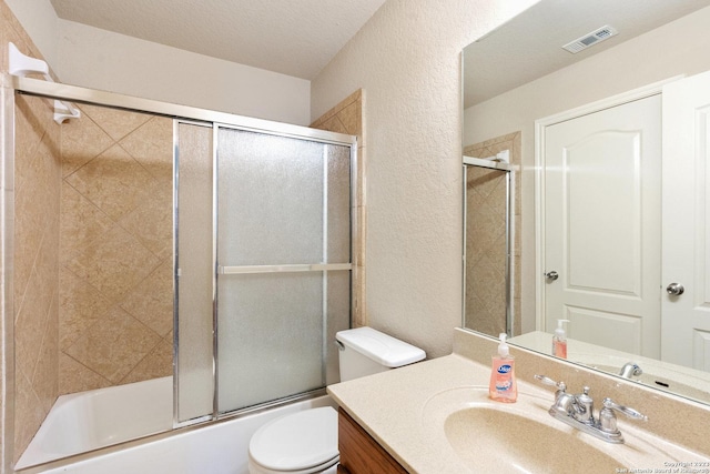 full bathroom featuring combined bath / shower with glass door, vanity, and toilet