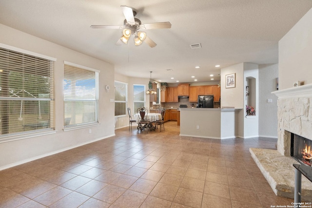 tiled living room with ceiling fan and a fireplace