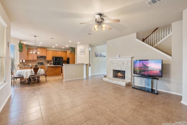 living room featuring a fireplace and ceiling fan with notable chandelier