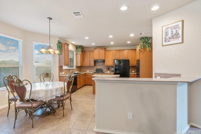 kitchen with tasteful backsplash, sink, black appliances, a notable chandelier, and hanging light fixtures