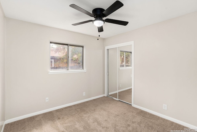 unfurnished bedroom with multiple windows, ceiling fan, a closet, and carpet