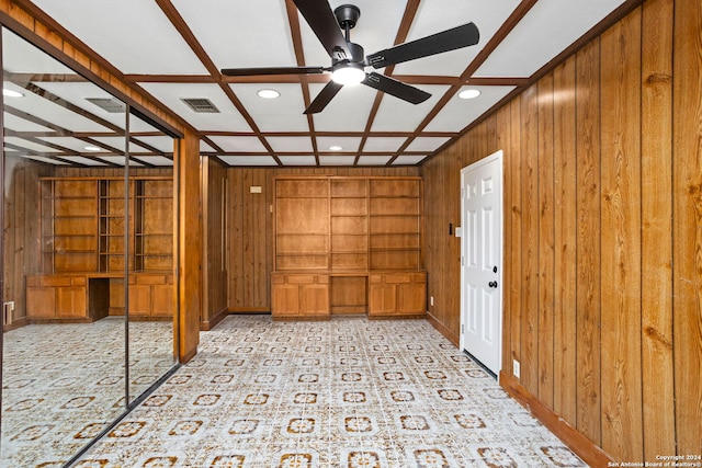 empty room featuring beamed ceiling, ceiling fan, wooden walls, and coffered ceiling