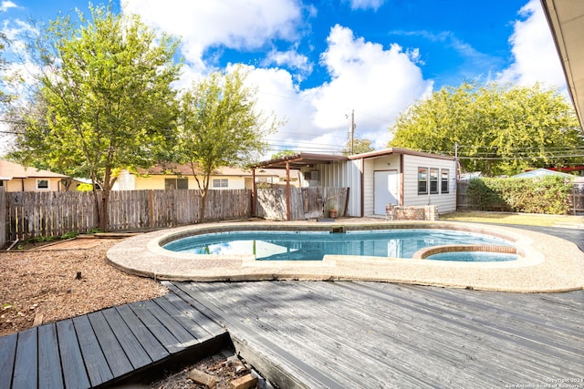 view of swimming pool with an outdoor structure, an in ground hot tub, and a wooden deck