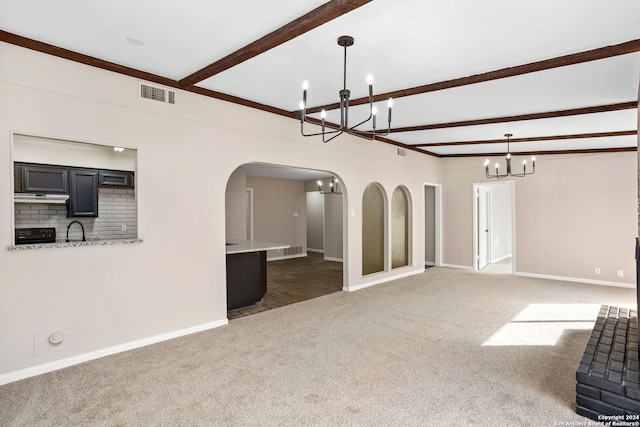 unfurnished living room featuring beam ceiling, sink, a notable chandelier, and dark colored carpet