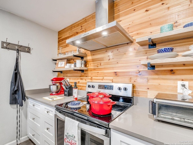 kitchen with white cabinets, wood walls, electric stove, and island range hood