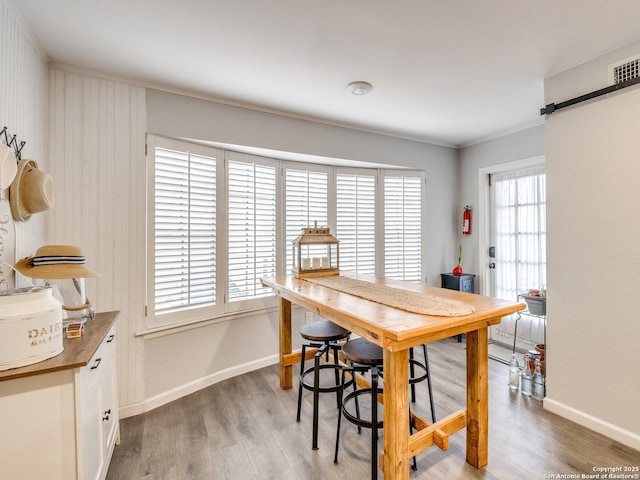 dining space with wood-type flooring and ornamental molding