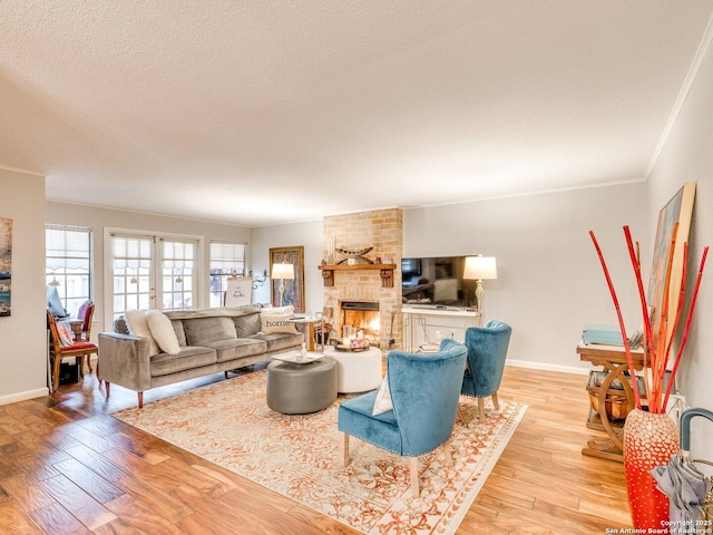 living room with a textured ceiling, light hardwood / wood-style floors, a brick fireplace, and crown molding