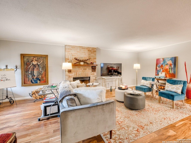 living room featuring a textured ceiling, light wood-type flooring, and a brick fireplace