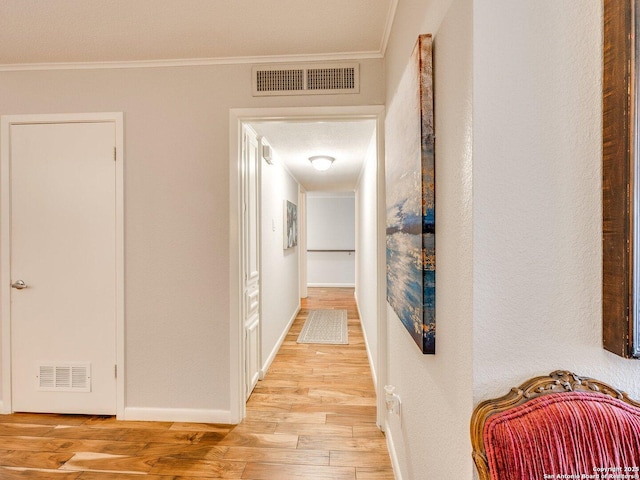 hallway with a textured ceiling, light hardwood / wood-style floors, and crown molding