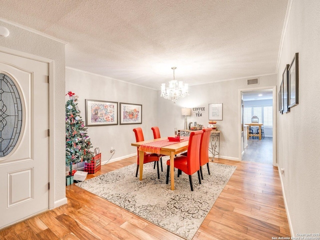 dining area with hardwood / wood-style floors, a notable chandelier, crown molding, and a textured ceiling