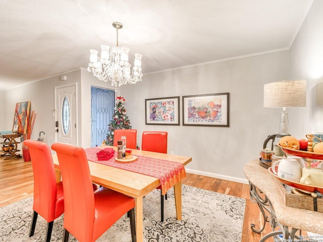 dining space with light hardwood / wood-style floors, crown molding, and an inviting chandelier