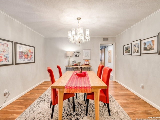 dining room featuring crown molding, a chandelier, a textured ceiling, and wood-type flooring