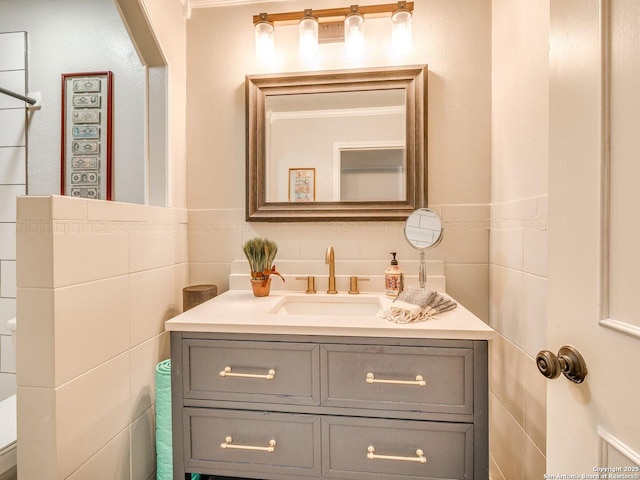 bathroom featuring vanity, tile walls, and toilet