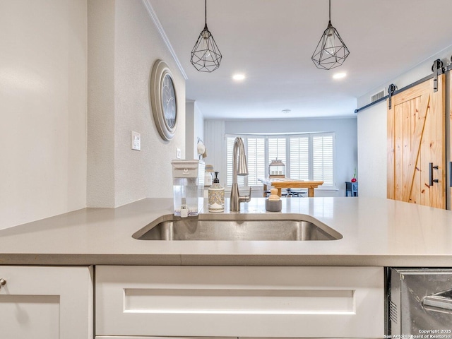 kitchen featuring a barn door, sink, and hanging light fixtures