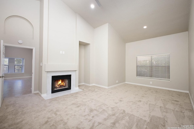 unfurnished living room featuring a towering ceiling and light colored carpet