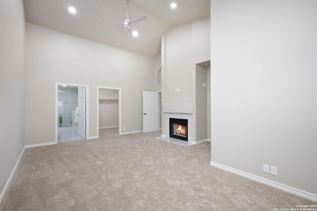 unfurnished living room with ceiling fan, light carpet, and high vaulted ceiling