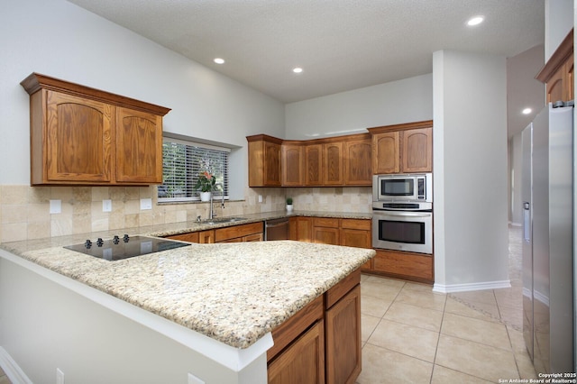 kitchen featuring sink, light stone counters, kitchen peninsula, light tile patterned floors, and appliances with stainless steel finishes