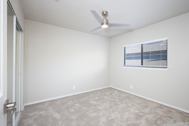 spare room featuring a textured ceiling, ceiling fan, and light carpet