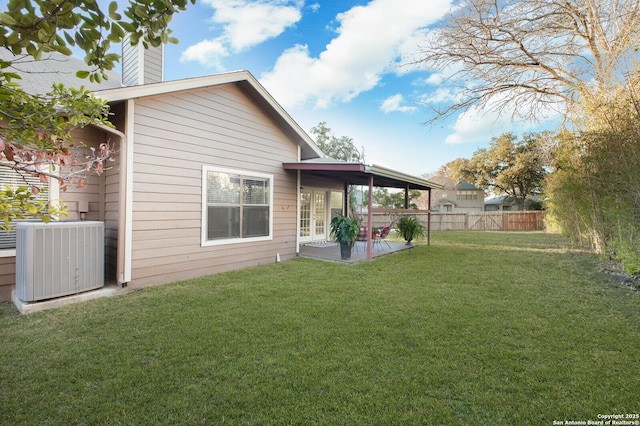 rear view of property with central AC unit, a patio area, and a yard